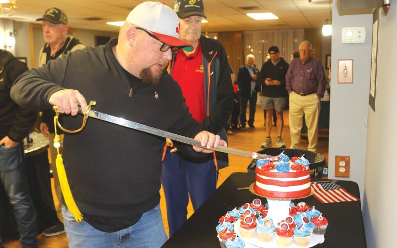 Kyle Warner, keynote speaker for the Lake City Elks Lodge #893 Marine Corps 250 birthday celebration, uses a sword to cut the birthday cake for the event. (TONY BRITT/Lake City Reporter)