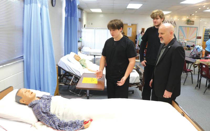 Fort White High School Health Occupation Science Academy students Jack Schroader (from left) and Christopher Meagher explain how they conduct a patient examination to FEA President Andrew Spar, who visited the school on a tour Tuesday afternoon. (TONY BRITT/Lake City Reporter)