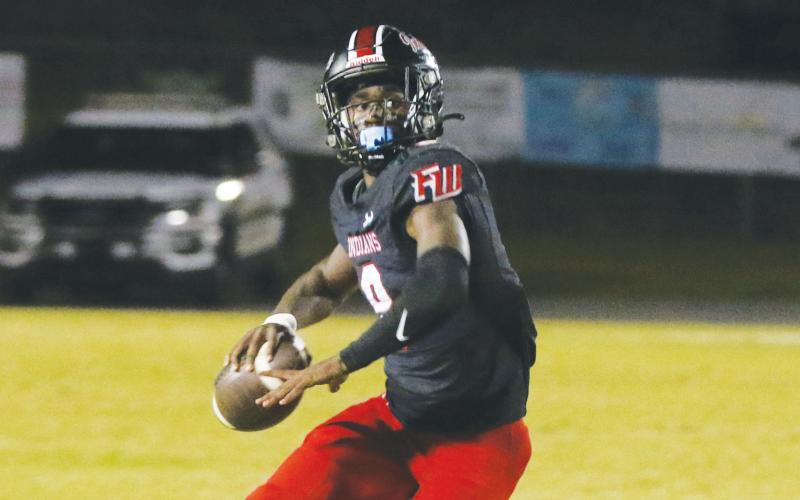 Fort White quarterback Jayden Jackson rolls out to pass during Friday’s win over Baker County. (MORGAN MCMULLEN/Lake City Reporter)