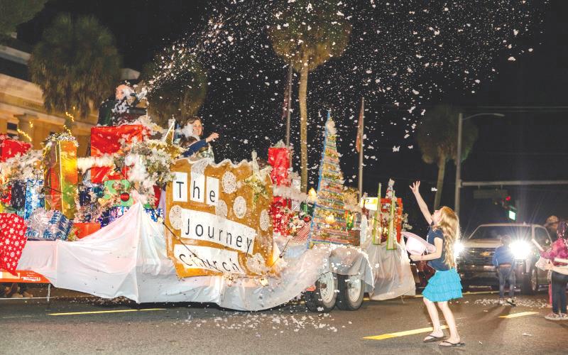 A girl tries to catch ‘snow’ blowing off The Journey Church’s float during a prior Downtown Christmas parade in Mayo. (FILE)