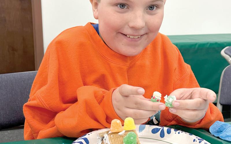 Donovan Corbett shows off some additions to his gingerbread house as he continued to work Monday during the 4-H STEM Explorers Club’s Christmas meeting. (COURTESY)