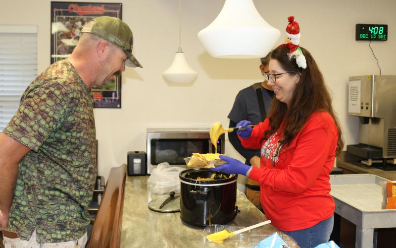 Matthew Isaacs (left), a U.S. Coast Guard veteran, gets a bowl of nachos and cheese from Karen Kraszewski, a recreational aide on Saturday at the Robert H. Jenkins Jr. Domiciliary where veterans watched the Army-Navy football game. (TONY BRITT/Lake City Reporter)