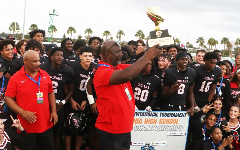 Fort White coach Demetric Jackson hoists the Rural FIT championship trophy following the Indians’ 32-29 win over Port St. Joe on Friday. (MORGAN MCMULLEN/Lake City Reporter)
