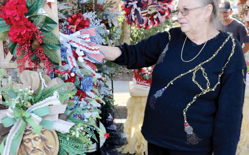 Deborah Water of Fort White, a vendor in the local holiday market, organizes Christmas wreaths in her booth. (TONY BRITT/Lake City Reporter)