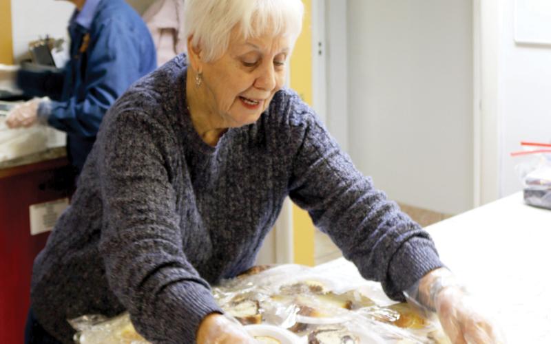 Anne Tatem covers desserts that were provided with dinner during food preparation for the cold weather shelter at Parkview Baptist Church. (TONY BRITT/Lake City Reporter)