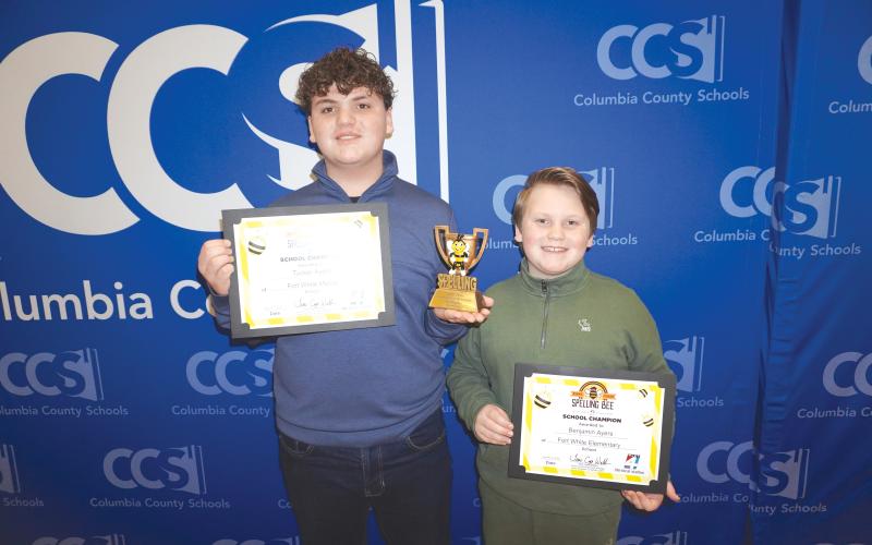 Fort White Middle School student Tucker Ayers (left) holds his certificate and trophy alongside his younger brother, Benjamin Ayers, after winning the 2026 Columbia County Schools First Coast Spelling Bee Friday. (COURTESY)