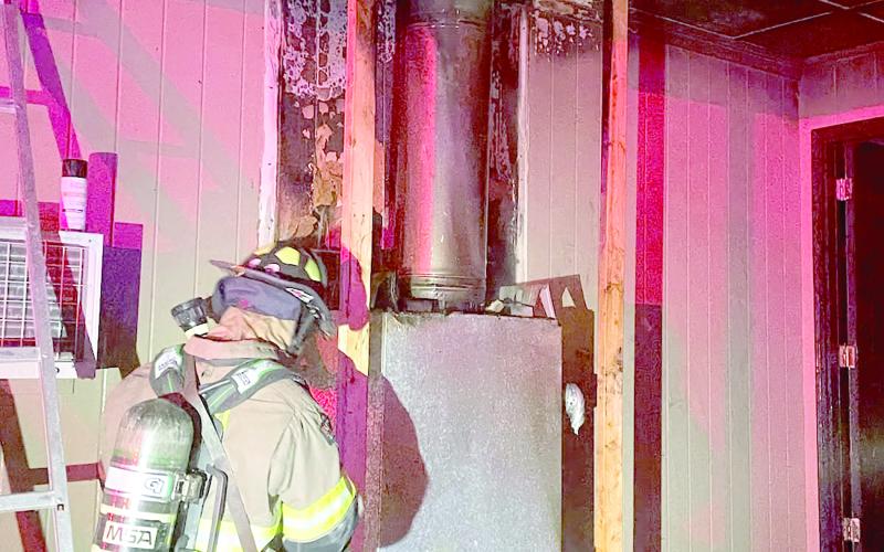 A Lake City firefighter helps extinguish a fire Tuesday night in a house off Siesta Place. The fire, which was found around the chimney for the house’s fireplace, was quickly extinguished and the home was still habitable. (COURTESY LAKE CITY FIRE DEPARTMENT)