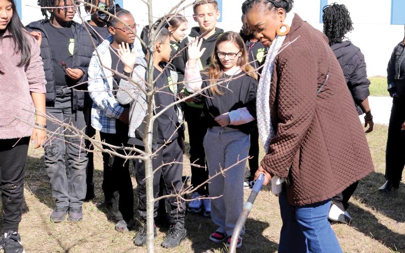 Niblack Elementary School Principal Makeba Murphy adds dirt to the hole where a Shumard Oak tree was planted at the school on Friday for Florida Arbor Day. The tree was donated by the Lake City Garden Club. (TONY BRITT/Lake City Reporter)