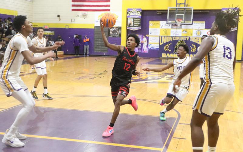 Fort White's Jonathan Bessent drives through the lane against Union County center Adrian Manns (left) and forward Tyrese Chandler during Thursday's District 6-R semifinal. (MORGAN MCMULLEN/Lake City Reporter)
