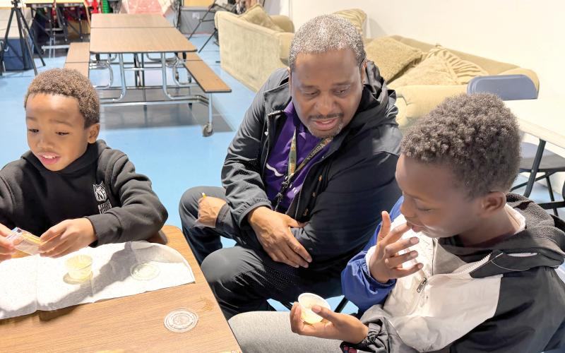Niblack Elementary physical education coach James Williamson coaxes students Augest and Kingston to try the results of their efforts in making butter. (COURTESY UF/IFAS EXTENSION COLUMBIA COUNTY)