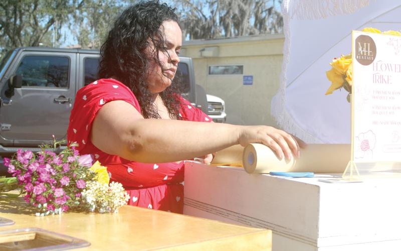 Jesenia Minniefield prepares a bouquet of flowers during last year’s Sweets in the Streets event in downtown Lake City. (FILE)
