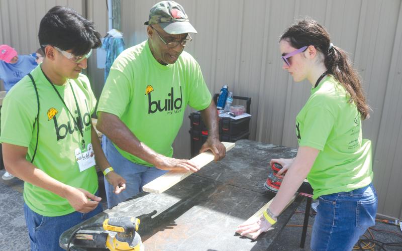 Angel Gomez, a Columbia High School student, gets tips on sanding wood from Monty Ashby, as Gomez and Kiley Morrison sand wood to make beds for the Sleep in Heavenly Peace program during last year’s Build My Future event. (FILE)