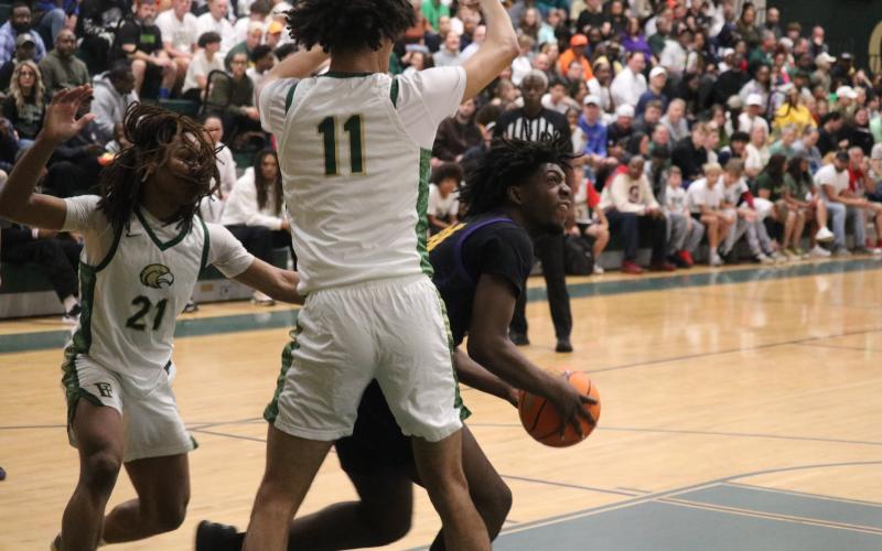 Columbia center Terrance Tolbert tries to find an opening to shoot while defended by Fleming Island guard Ayden Greenidge (21) and center Jalil Hill (11) during the Region 1-5A finals on Saturday. (JORDAN KROEGER/Lake City Reporter)