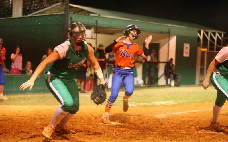 Branford pinch runner Payton Bates scores the tying run as Suwannee's Felicity May chases the ball on Monday. (PAUL BUCHANAN/Lake City Reporter)