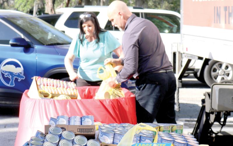 April Powell (left) and Todd Denmark, Circle of Life Assisted Living Facilities employees, unload bags of food stable items that were donated to Catholic Charities during the March Against Hunger event on Thursday afternoon. Circle of Life Assisted Living facilities contributed 1,126 canned goods to the food collection drive. (TONY BRITT/Lake City Reporter)