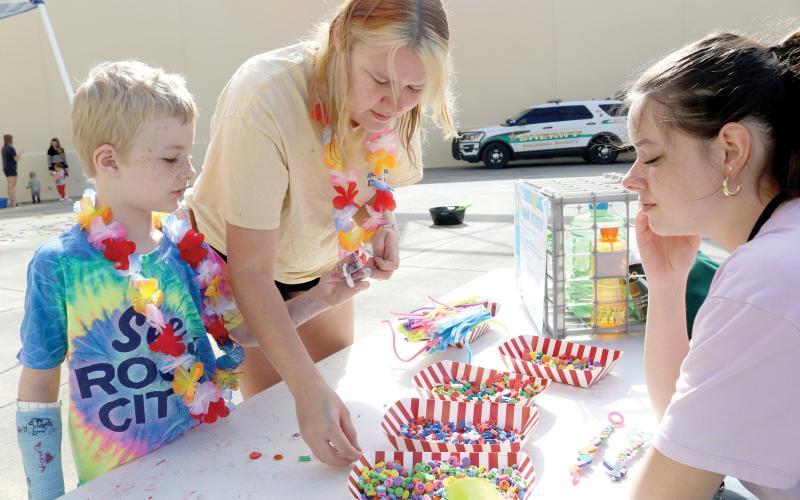 Ryan Poirier (clockwise from left), 6 and Callie Poirier make a bubble wand with help from Bella Heser during the MESS-tival event at the West Branch Library on Thursday morning. (TONY BRITT/Lake City Reporter)