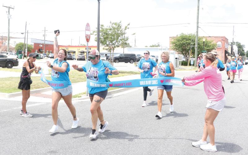 Local walkers cross the finish line in downtown Lake City on Tuesday morning after completing the eight-mile Lauren’s Kids Walk in My Shoes event. It’s the first time the statewide walk has made a stop in Lake City. (MORGAN MCMULLEN/Lake City Reporter)