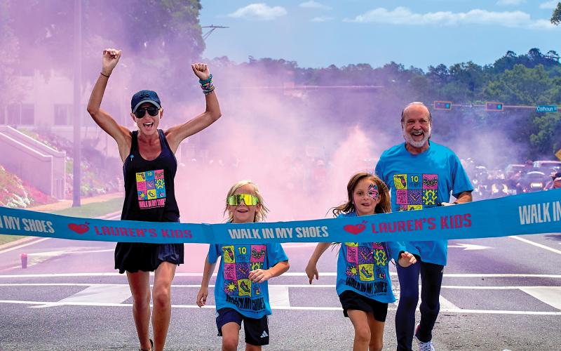 Lauren Book, a survivor and the founder of Lauren’s Kids, completes a walk at one of the stops during last year’s Lauren’s Kids Walk, along with a pair of children and her father, Ron. (COURTESY)
