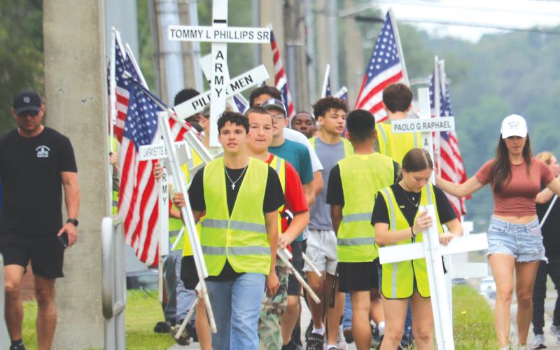 Columbia High School JROTC cadets carry flags and crosses that will be placed alongside State Road 47 in honor of veterans and first responders. (TONY BRITT/Lake City Reporter)