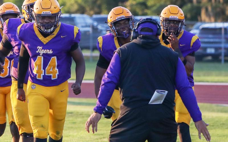 Columbia defensive end Mikel Morgan (middle) races to celebrate with defensive coordinator Chris Martinez (middle) after returning a fumble for a touchdown against Camden County in Friday’s spring game. (BRENT KUYKENDALL/Lake City Reporter)