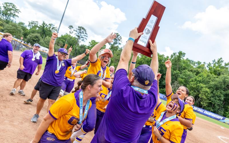 Columbia coach Joe Saucier hoists the Class 4A state championship trophy to his team as the Tigers celebrate following their 3-2 win over Lake Wales on Saturday. (JACK HOWDESHELL/Lake City Reporter)