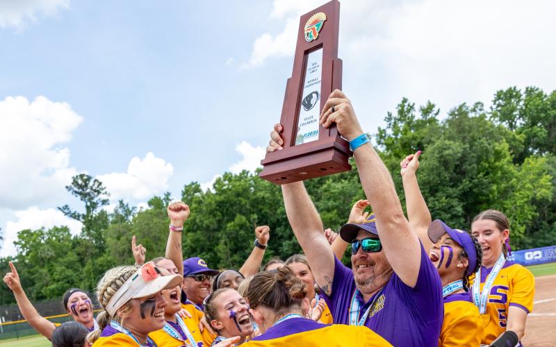 Columbia coach Joe Saucier hoists the Class 4A state championship trophy to his team as the Tigers celebrate following their 3-2 win over Lake Wales on Saturday. (JACK HOWDESHELL/Lake City Reporter)