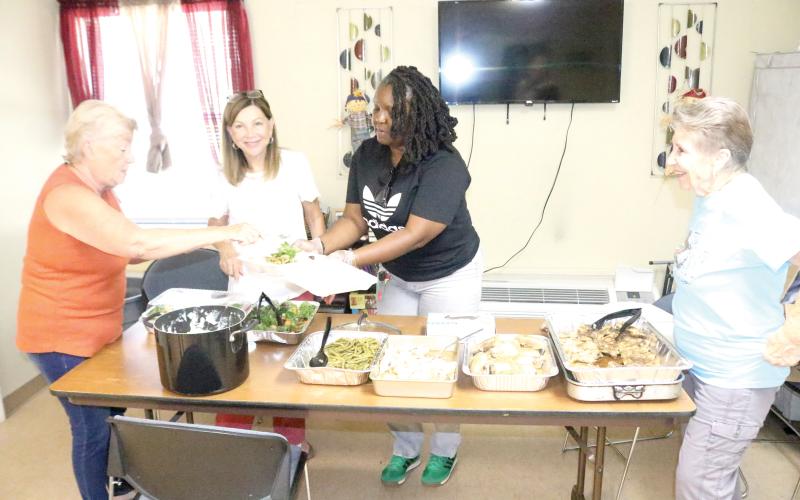 Trish Webb (from left), Roseanna Lee, Tanzania Williams and Bonnie Page prepare to-go plates for veterans who reside in the Lake City Cabins for Veterans on Friday afternoon. The Columbia County Executive Committee provides the lunches, free, on the last Friday of every month. (TONY BRITT/Lake City Reporter)