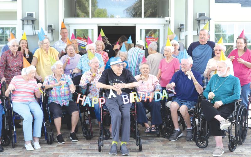 Del Porter (center) is all smiles as The Heron on Lake City residents wish him a happy 100th birthday on Thursday afternoon. (TONY BRITT/Lake City Reporter)