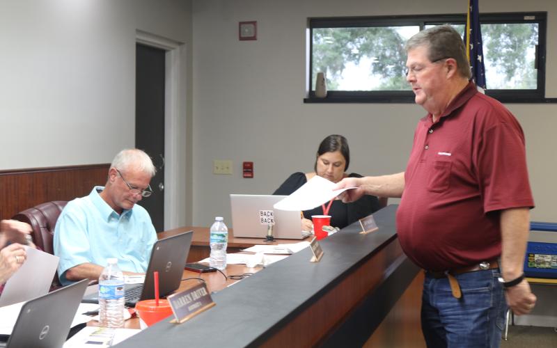 Eddie Dixon with Culpepper Construction provides documents to the Lafayette County School Board as he updated them on the status of state funding for a new PK-12 school for the district at Tuesday’s board meeting. (TONY BRITT/Lake City Reporter)