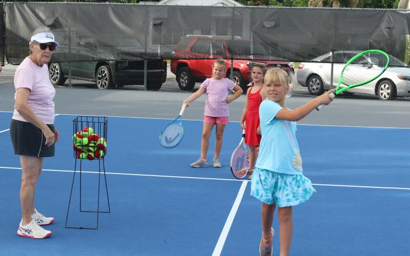 Marcia Kazmierski (left) watches as Jensen Haire, 8, hits a tennis ball during the 10th annual James Montgomery Tennis Camp at Youngs Park on Thursday. (TONY BRITT/Lake City Reporter)