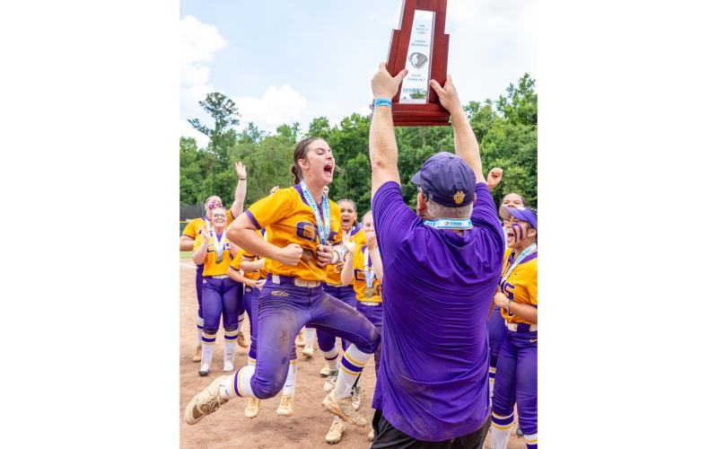 Columbia shortstop Alannah Lord (left) celebrates as coach Joe Saucier (right) hoists the Class 4A state championship trophy after the Tigers defeated Lake Wales for the title on May 23. (JACK HOWDESHELL/Lake City Reporter)