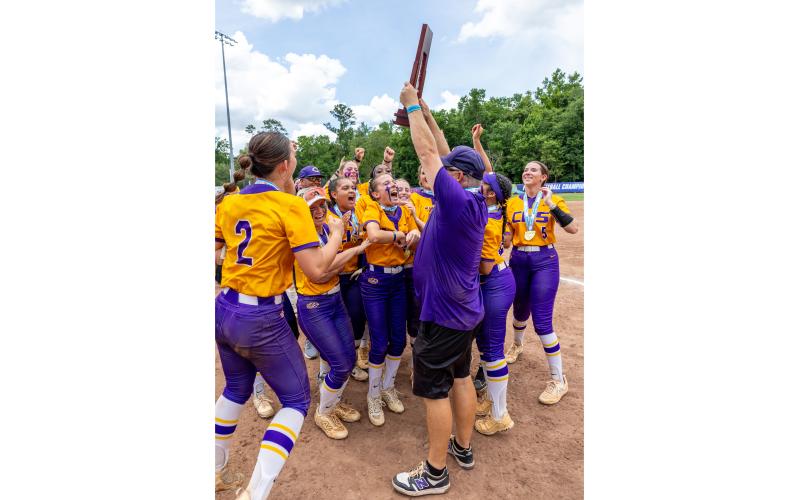 Columbia’s softball team celebrates as head coach Joe Saucier raises the Class 4A state championship trophy after the Tigers defeated Lake Wales on May 23. (JACK HOWDESHELL/Lake City Reporter)