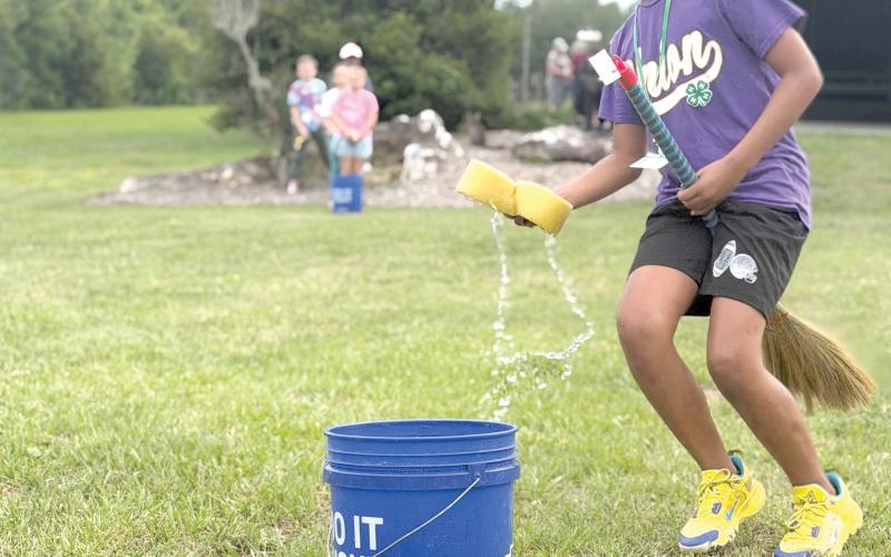 Zayden Jones learns the art of broom handling while participating in a relay race during Columbia County 4-H’s School of Life Skills for Magical Beings camp earlier this month. (COURTESY)
