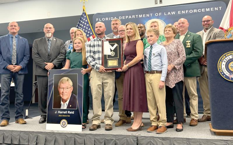 Kathryn Land and J. Reid, former Hamilton County Sheriff Harrell’s Reid’s children, hold his encased medallion after he was posthumously inducted into the Florida Law Enforcement Officers Hall of Fame on Saturday. Land and Reid were surrounded by family members and past and present members of the Hamilton County Sheriff’s Office. (COURTESY)