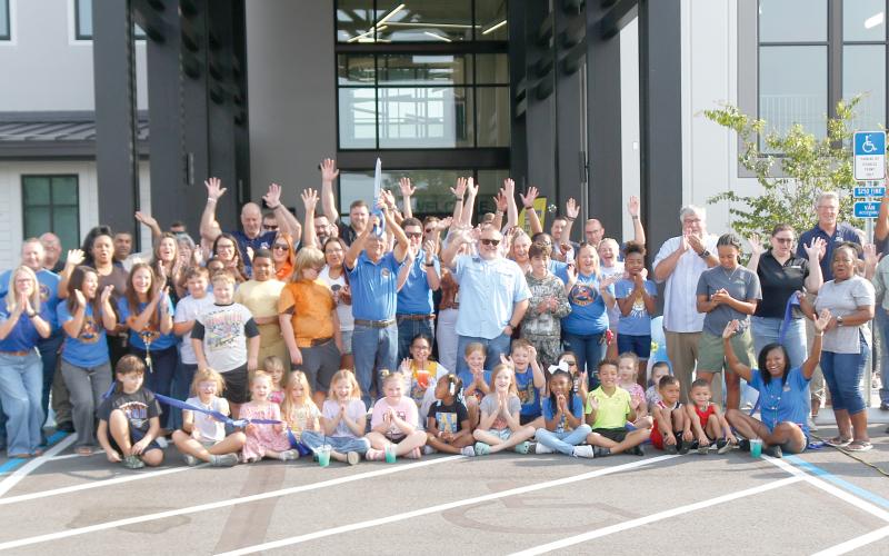 Columbia County School Board member Keith Hudson holds up the scissors after cutting the ribbon to open up the new Eastside Elementary School on Tuesday morning. Hudson is joined by students, faculty and staff at Eastside as well as school district officials and members of the Gilbane Construction company that built the new school. (JAMIE WACHTER/Lake City Reporter)
