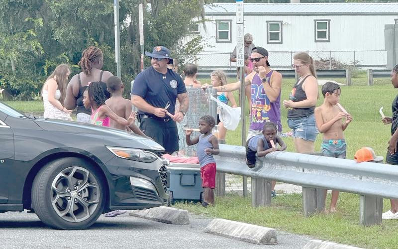 Lake City firefighter Earl Lupardus hands out popsicles to children at the Lake City Fire Department’s ‘Pop-Up Community Sparh Party’ at Annie Mattox Park on Friday. (COURTESY LAKE CITY FIRE DEPARTMENT)