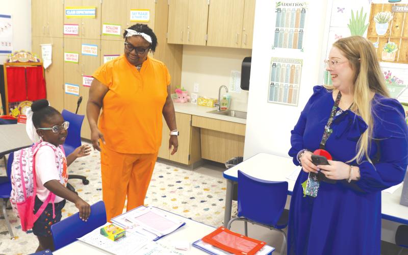Jordynn Cray (left) prepares to get settled into the kindergarten classroom of Brittany Townsend (right) during the first day of classes at the new Eastside Elementary School. (TONY BRITT/Lake City Reporter)