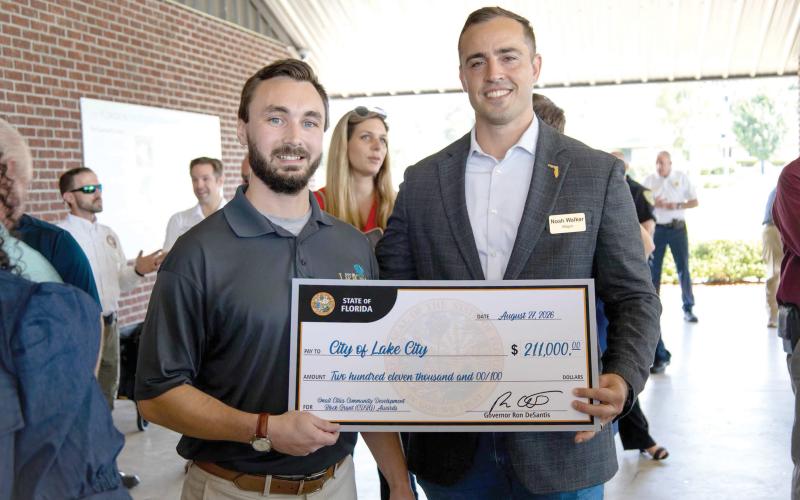 Lake City Mayor Noah Walker (right) and Dakota Braun, the city’s grant writer, hold the city’s ceremonial check for $211,000 that it received Thursday for a street paving project. (COURTESY CITY OF LAKE CITY)