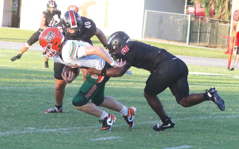 Fort White defensive linemen Josiah Harmon and Cillian Sheehan (40) tackle Eastside quarterback Cade Sutherland for a loss last Friday. (MORGAN MCMULLEN/Lake City Reporter)