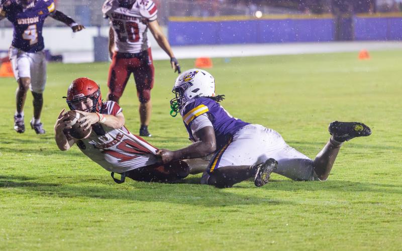 Lafayette quarterback Tucker Higginbotham stretches out for extra yards as he is wrapped up by a Union County defender Friday night. (JACK HOWDESHELL/Lake City Reporter)