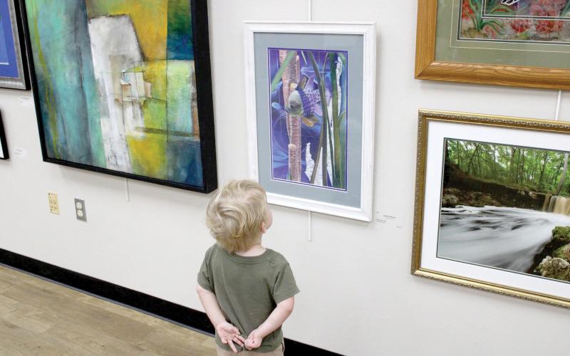 A young art fan checks out some of the works in last year’s Autumn Artfest, the fine arts exhibition sponsored by the Live Oak Artists Guild. The 28th annual Artfest opens Saturday at the Live Oak branch of the Suwannee River Regional Library. (COURTESY)