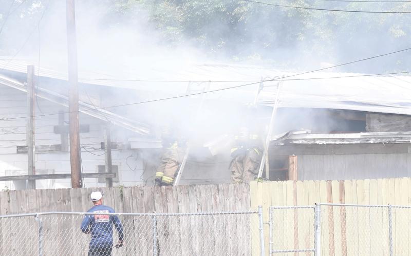 Lake City firefighters combat a fire in an attic space of a house on NW Burk Avenue late Thursday morning. (JAMIE WACHTER/Lake City Reporter)