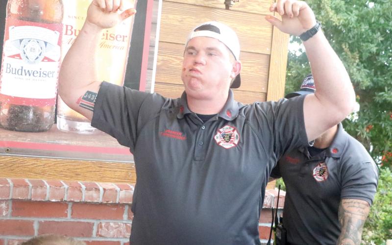 Lake City Fire Department Engineer Trenton Kreienheder raises his arm in triumph after completing his leg of the rib-eating contest Tuesday night at Texas Roadhouse. (MORGAN MCMULLEN/Lake City Reporter)