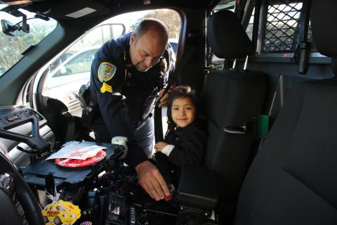 Lake City Police Department officer Robert Milligan belts in Olivia Dillow, 5, as they prepare to head out for the Lake City Police Department after a morning of shopping. (TONY BRITT/Lake City Reporter)