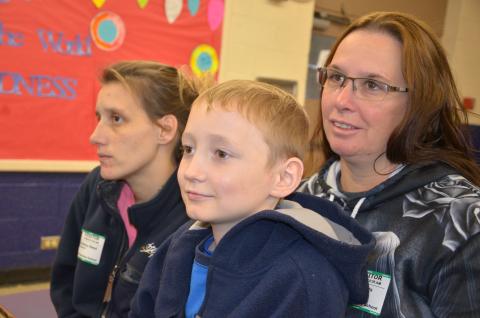 Hunter Dover, soon to turn 9, sits in his grandmother’s lap during a presentation at Five Points Elementary welcoming him back to school after a long absence. (CARL MCKINNEY/Lake City Reporter)