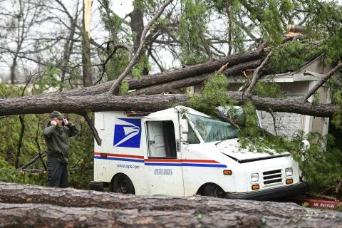 A man talks on the phone next to a damaged postal truck at an apartment complex where heavy weather passed through Thursday in Spartanburg, S.C. (SEAN RAYFORD/Associated Press)