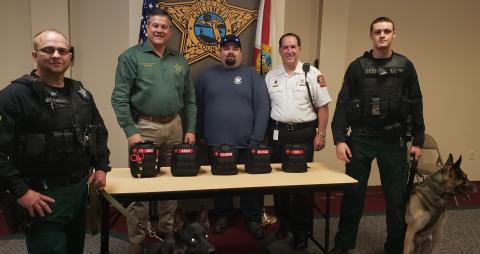 The Columbia County Sheriff’s Office accepts five K9 emergency first aid kits from Century Ambulance, the county’s EMS provider. Sheriff Mark Hunter, second-left, held a photo op with Century’s operations manager for the area, Steve Stith, pictured in the white uniform, along with K9 Drago, K9 Rek and their human counterparts. (COURTESY)