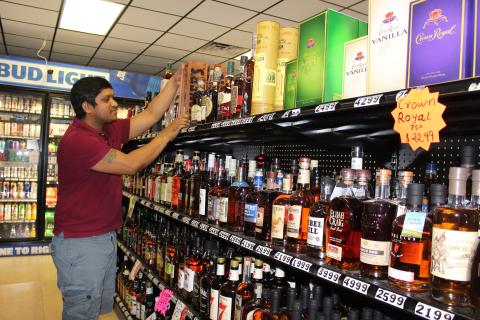 Dharmendra Thakor, manager of A&D Discount Liquor, at the corner of Main Street and U.S. 90, straightens a top-shelf bottle of Booker’s bourbon at his store in downtown Lake City Friday afternoon. Thakor said since the coronavirus pandemic hit his business has been good, as people have increased spending on liquor and beer, buying larger quantities and more frequently. (TODD WILSON/Lake City Reporter)