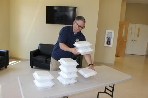 Rotary Club of Lake City Treasurer Mike Tatem stacks boxed-lunch meals at noon Thursday inside the welcome center at Parkview Baptist Church. Rotarians drove through the covered drop-off area of the church, picked up a lunch, then returned home or to their offices before tuning in to the club’s first-ever virtual meeting via the on-line platform Zoom. The club normally meets at noon on Thursdays. (TODD WILSON/Lake City Reporter)