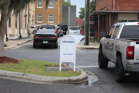 Vehicles wait in line to enter the two lanes of the drive-through at the Columbia County Tax Collectors office Monday afternoon. Property owners also may drop their tax payment checks in the white drop box, center, or call and pay by phone with a credit card or pay online at: www.columbiataxcollector.com. (TODD WILSON/Lake City Reporter)
